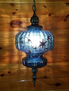 a blue glass light hanging from a wooden wall