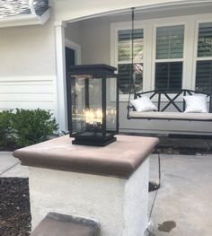 two lit candles sitting on top of a cement block in front of a porch swing