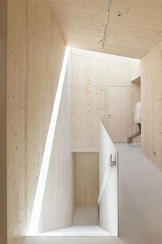 an empty room with wooden walls and white stairs leading up to the upper floor area