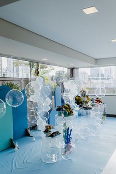 an indoor event with balloons and decorations on the table in front of large glass windows