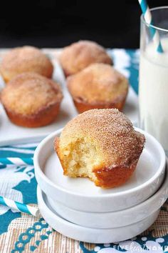 some sugary muffins are on plates next to a glass of milk