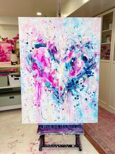 an abstract painting is being displayed in a room with pink and blue paint splattered on