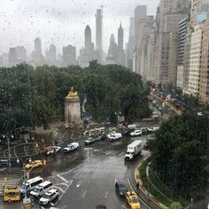 a city street filled with lots of traffic next to tall buildings in the rain covered sky