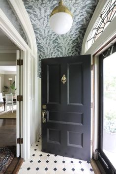 a black door in a white room with patterned walls and floor tiles on the floor