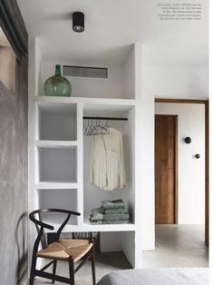 a bedroom with white walls and shelves filled with towels