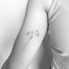 a black and white photo of a woman's arm with a single flower tattoo on it