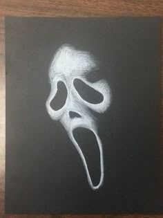 a chalk drawing of a scream mask on a blackboard