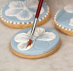 a cookie decorated with blue and white icing has a paintbrush in the center