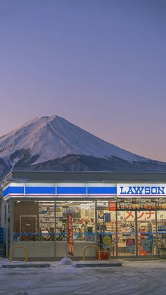 a building with snow on the ground and a mountain in the background