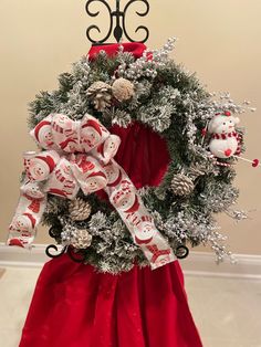 a christmas wreath on top of a stand with ornaments around it and snowman decorations