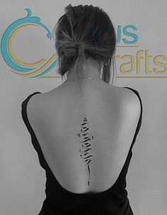 a woman with a tattoo on her back is standing in front of a white wall