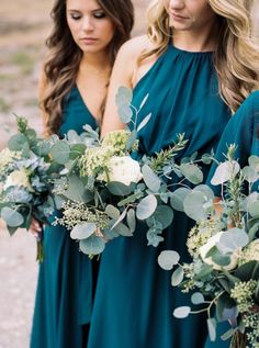 two bridesmaids in green dresses holding bouquets of greenery and eucalyptus leaves