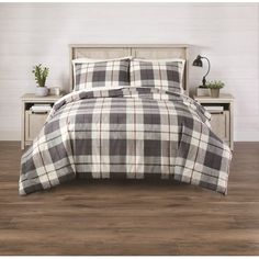 a bed with a plaid comforter and pillows on it in a room next to a night stand