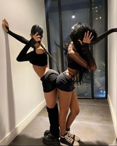 two women in short shorts and knee high boots are posing for the camera with their hands behind their backs