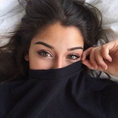 a woman laying on top of a bed with her eyes covered by a black blanket