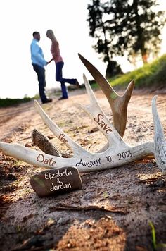 two antlers with names on them sitting in the dirt next to a couple walking