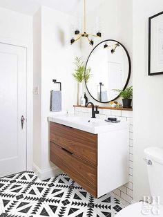 a bathroom with black and white flooring and a round mirror on the wall above the sink