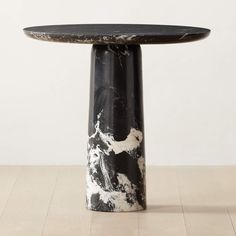 a black and white table sitting on top of a wooden floor next to a wall