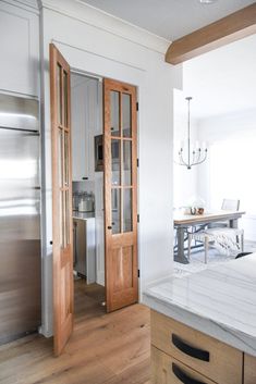 a kitchen with an island and stainless steel refrigerator in the center, next to a dining room table