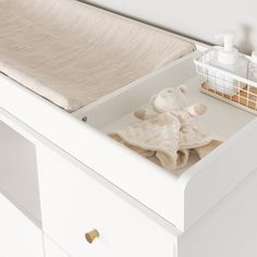 an open drawer with towels and soaps in it on top of a white dresser