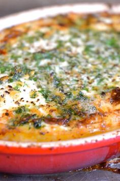 a casserole dish sitting on top of a pan covered in cheese and herbs