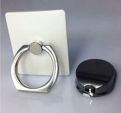 a pair of metal rings sitting next to a white tabletop with a black ring on it