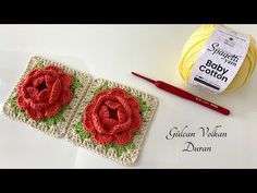 two crocheted coasters with red flowers on them and yarn next to it