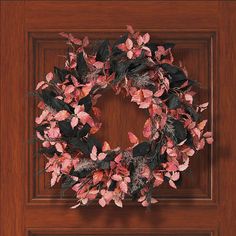 a wooden door with a wreath hanging on it's side and leaves around the edges