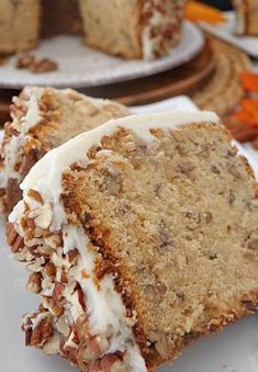 two slices of carrot cake with white frosting and pecans on the top one slice is cut in half