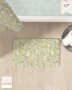 a bathroom rug with flowers and leaves on the floor next to a bathtub, toilet paper roll and towel rack