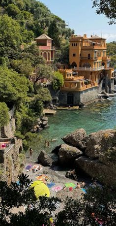 people are relaxing on the beach in front of an orange house and some green trees