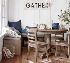 a dining room table with chairs and a bench in front of the window that reads gather