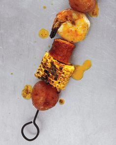 a grilled meat and vegetable skewer on a metal surface with sauce drizzled around it