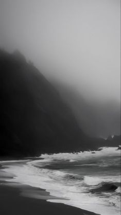 a black and white photo of the ocean on a foggy day