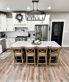 a kitchen with white cabinets and marble counter tops