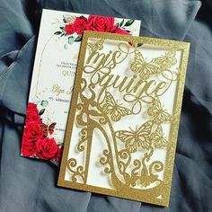 the wedding card is decorated with gold glitter and red roses, along with an envelope