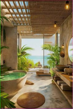 a bathroom with a large bathtub next to the ocean and palm trees on either side