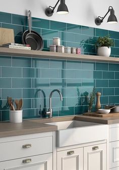 a kitchen with white cabinets and blue tile backsplash, hanging lights above the sink