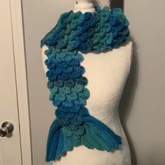 a white mannequin with a blue and green knitted scarf on top of it