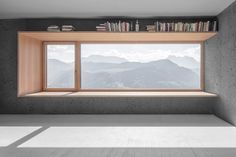 an empty room with bookshelves and windows overlooking the mountain range in the distance