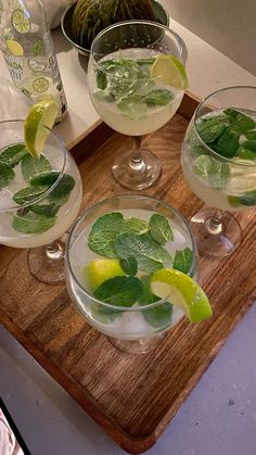 three glasses filled with drinks sitting on top of a wooden tray