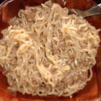 a bowl filled with noodles and meat on top of a table