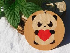 a wooden ornament with a panda holding a heart on it's chest