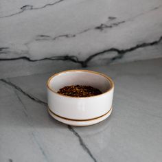 a white bowl filled with food sitting on top of a marble counter next to a wall