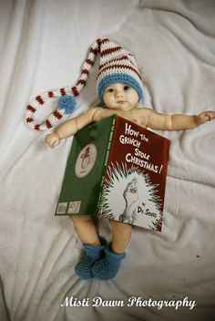 a baby doll laying on top of a bed with a book in it's hands