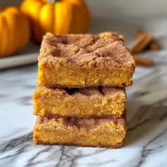 three pieces of cake sitting on top of a counter next to oranges and cinnamon sticks