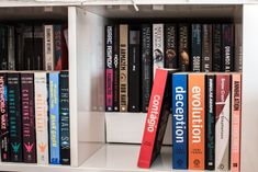 a book shelf filled with lots of books on top of white shelve shelves