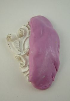 a pink and white brooch sitting on top of a table