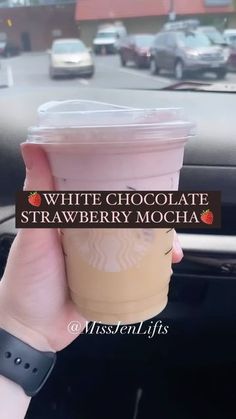 a person holding up a cup of coffee in their hand with the words white chocolate strawberry mocha on it