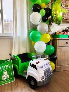 a green and white truck parked next to a bunch of balloons